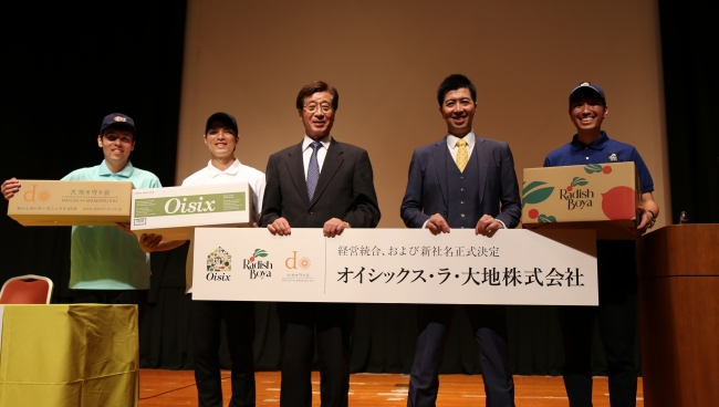 新社名のパネルをもつ当社会長の藤田和芳(左)と社長の高島宏平(右)
