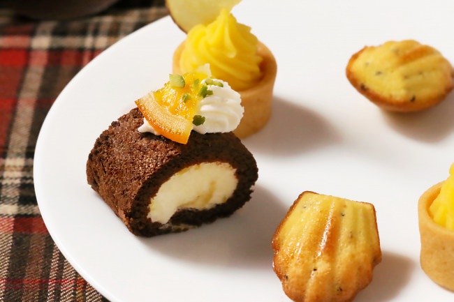 前から、マドレーヌ アールグレイ  左：オレンジショコラ ロールケーキ  左奥：スイートポテト タルト