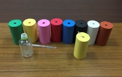 図１：実験で用いられた各色彩条件の容器。透明のペットボトルを色画用紙の筒で包装し、水溶液が直接見えないようにした。